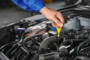 male mechanic checking engine oil level in car service